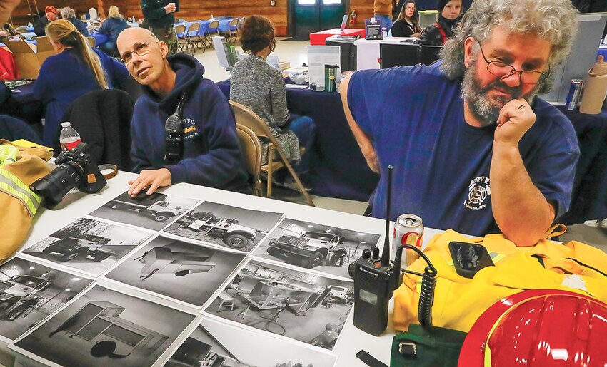 Embarrass Fire Chief Tom Martin and   firefighter Eric Garman display photos of the   creation of their new fire truck at the recent winter   festival at Timber Hall.