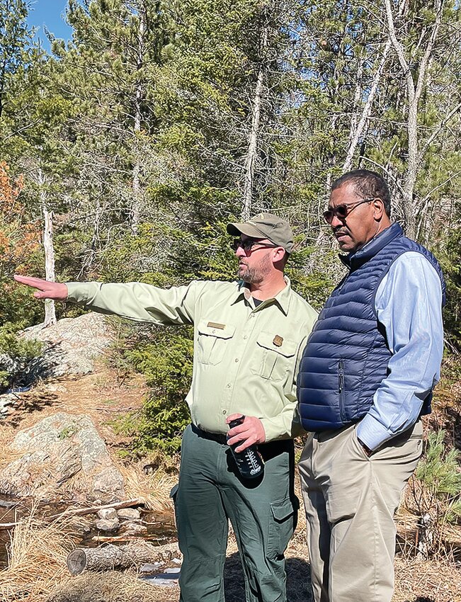 Kawishiwi District Ranger Aaron Kania gestures while pointing out recent fuel  reduction work along Slim Lake to Under Secretary Wilkes.