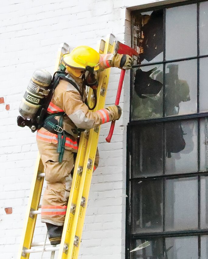 Greenwood   firefighter Brian Trancheff knocks 140-year-old glass from a window in the engine house at the Soudan Mine to ventilate smoke from a small fire in the building.