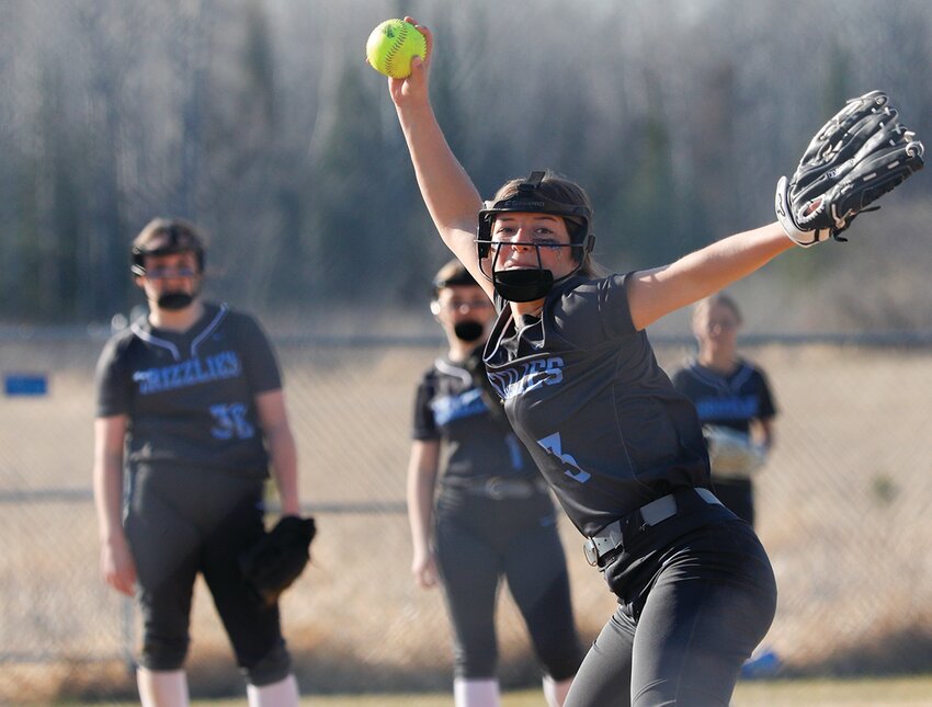 Grizzlies hurler Addison Burckhardt winds for a pitch with a group of North Woods defenders backing her up during last Thursday&rsquo;s game with Mt. Iron-Buhl.
