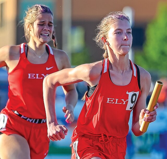 Grace LaTourell grimaces in relief after handing off the baton to  Violet Udovich during state competition in the 4x400 relay.