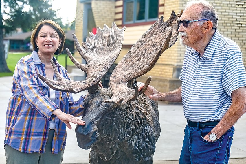 During a visit to Cook last week, Sen. Amy Klobuchar uses the moose in front of the library to show the height of the floodwaters as Mayor Harold Johnston looks on.
