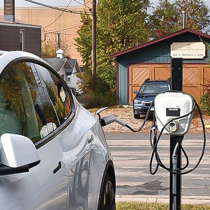An electric car charges at a port outside the Ely Public Library.