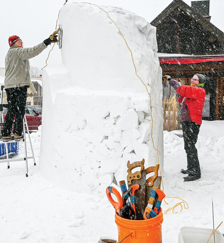 Snow sculptors Claudia McBride (l) and Nancy Scheibe begin work   on the official &ldquo;pin&rdquo; sculpture   crafted each year in front of Piragis Northwoods Co. at the intersection of Central and Sheridan.