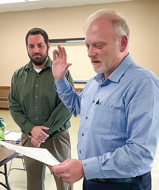 John VanDeVoort raises his hand as he recites the oath of office with Clerk-Treasurer Michael Schultz looking on