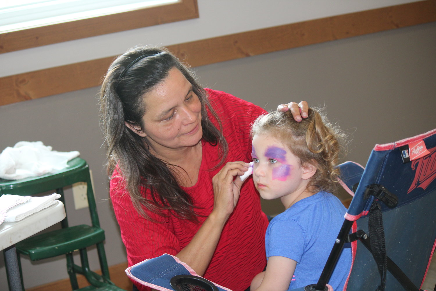 Tracey Robinson paints the face of Maren Foss, 2, of Cook inside the community center.