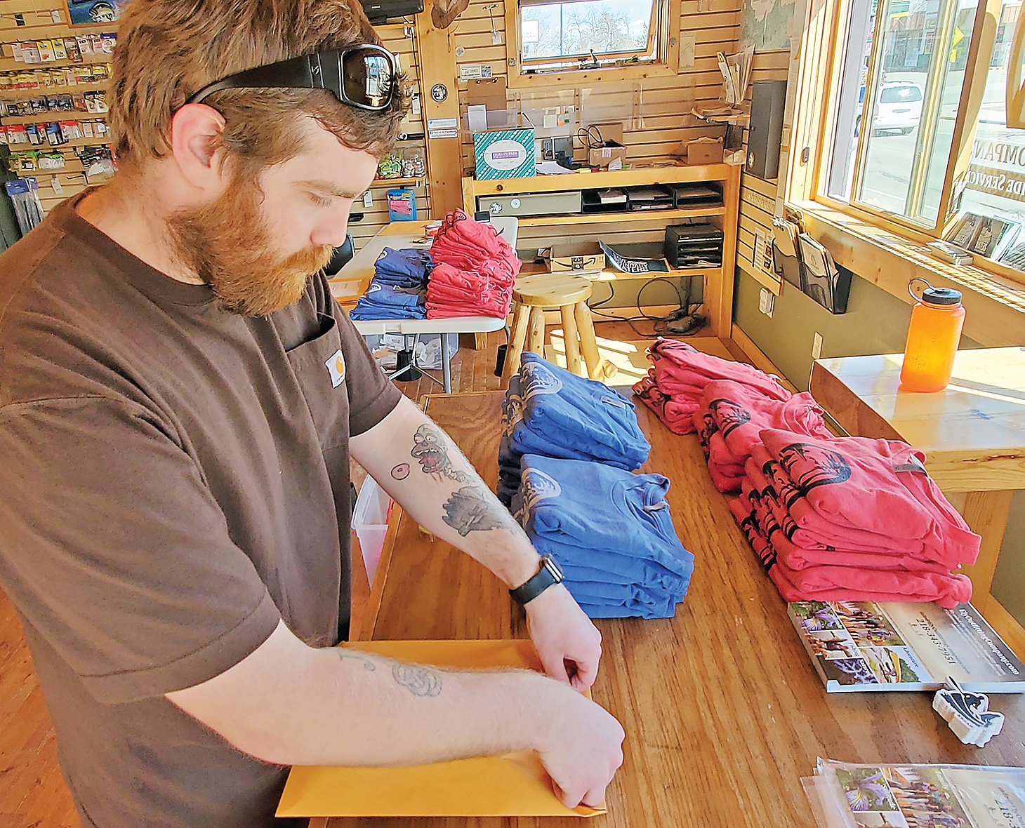 Nick Bailles, of Ely Outfitting, packages t-shirts made famous by a new best-selling romantic comedy.