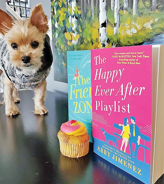 Author Abby Jimenez’s dog Stuntman Mike with the cover of her new book and a cupcake.
