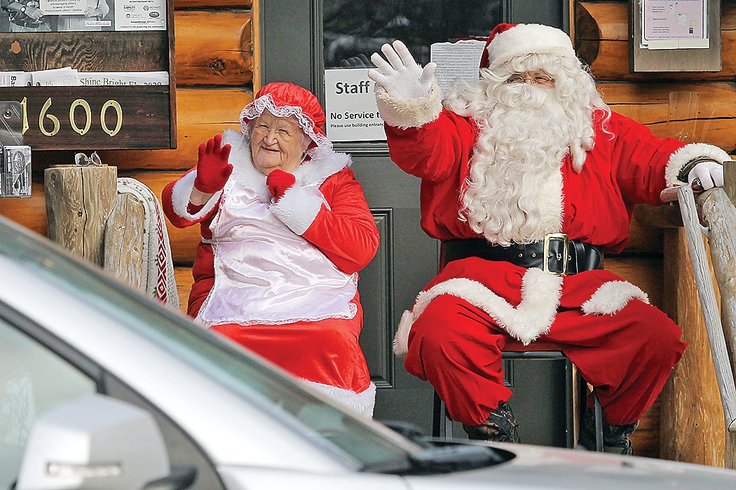 Santa and Mrs. Claus wave to cars passing by.