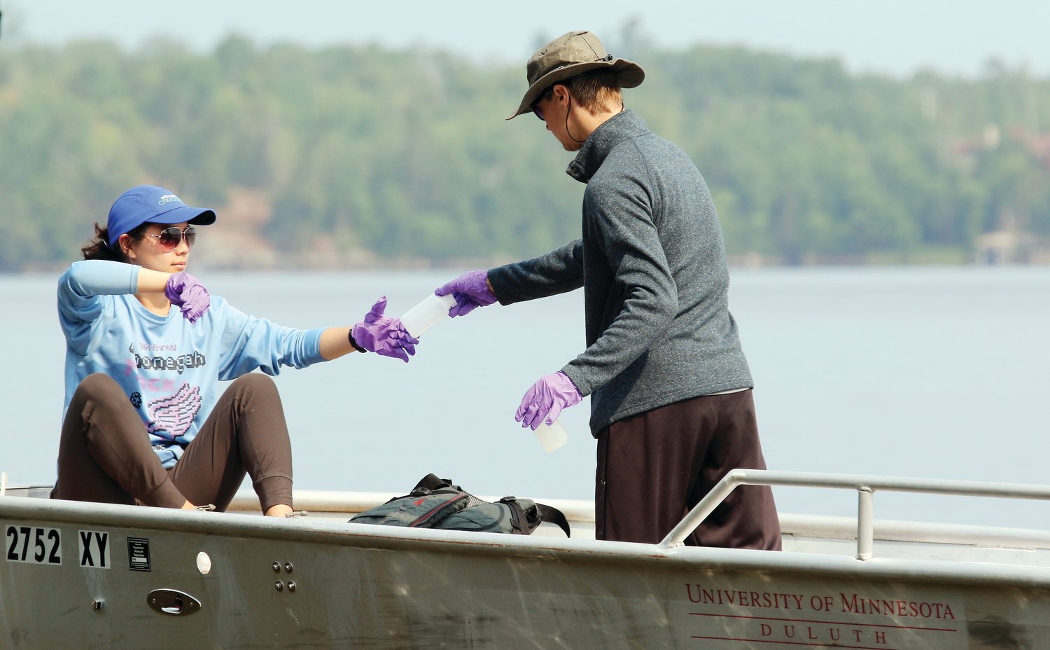 NRRI grad student Anna Totsch takes a bottle from research assistant Collin Krochalk, a UMD undergrad who is working for the NRRI this summer. 
They were gathering water samples on Frazer Bay on Monday.