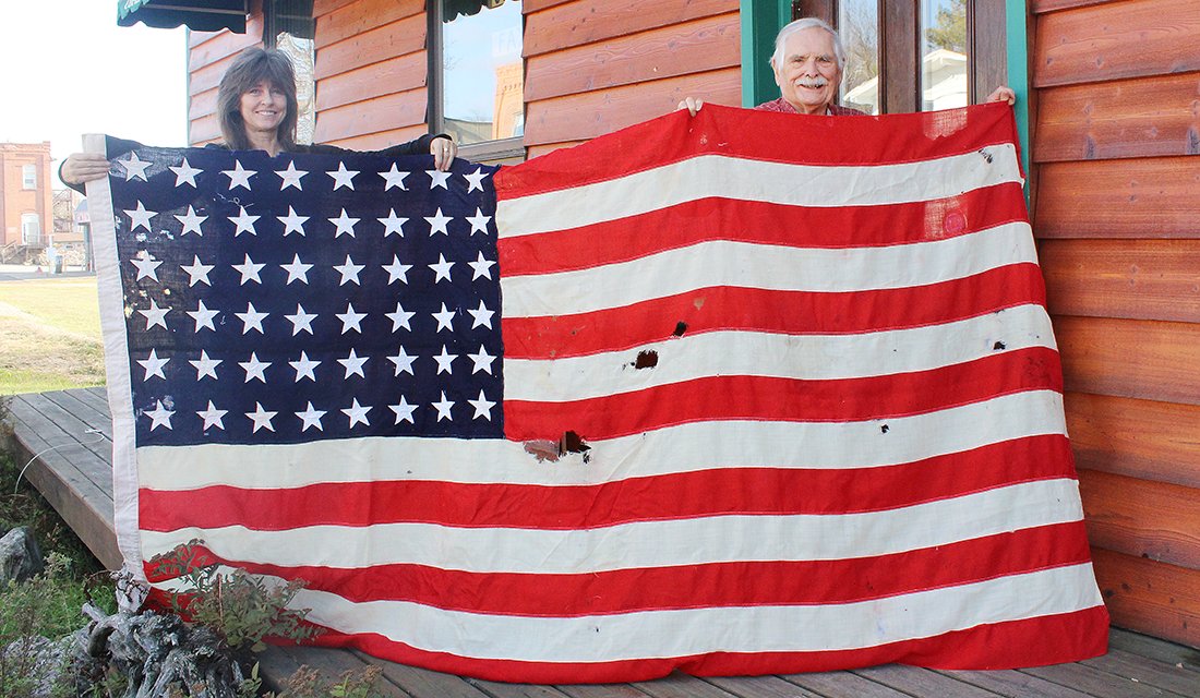 Tower resident Clair Helmberger and Richard Hanson, museum curator of the Tower-Soudan Historical Society, display a 48-star American flag that once draped the coffin of the first area soldier to be killed in 
battle in World War I.