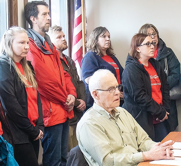 ISD 2142 school board member Robert Larson was surrounded by district teachers Tuesday night as Local #1406 union members stood in solidarity over stalled contract negotiations.