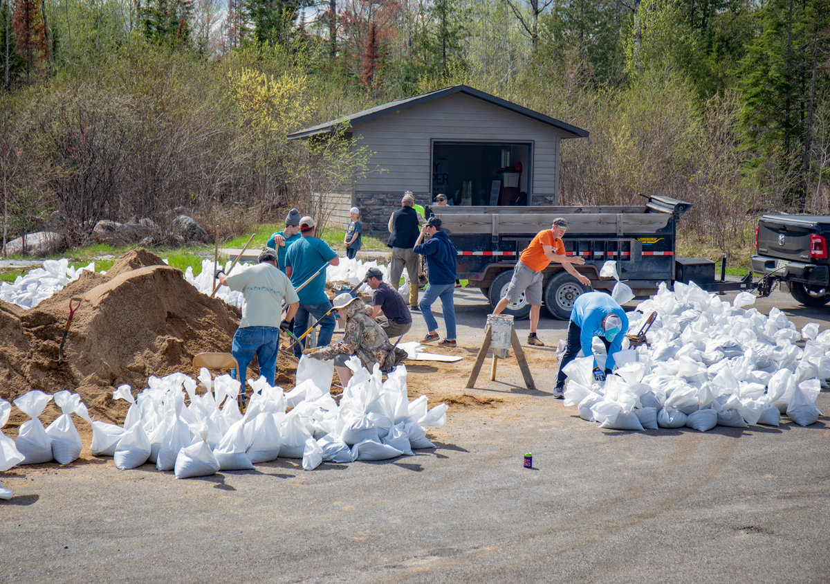 Volunteers scramble to fill sandbags in Kabetogama on Saturday afternoon to try to keep ahead of rising lake levels.