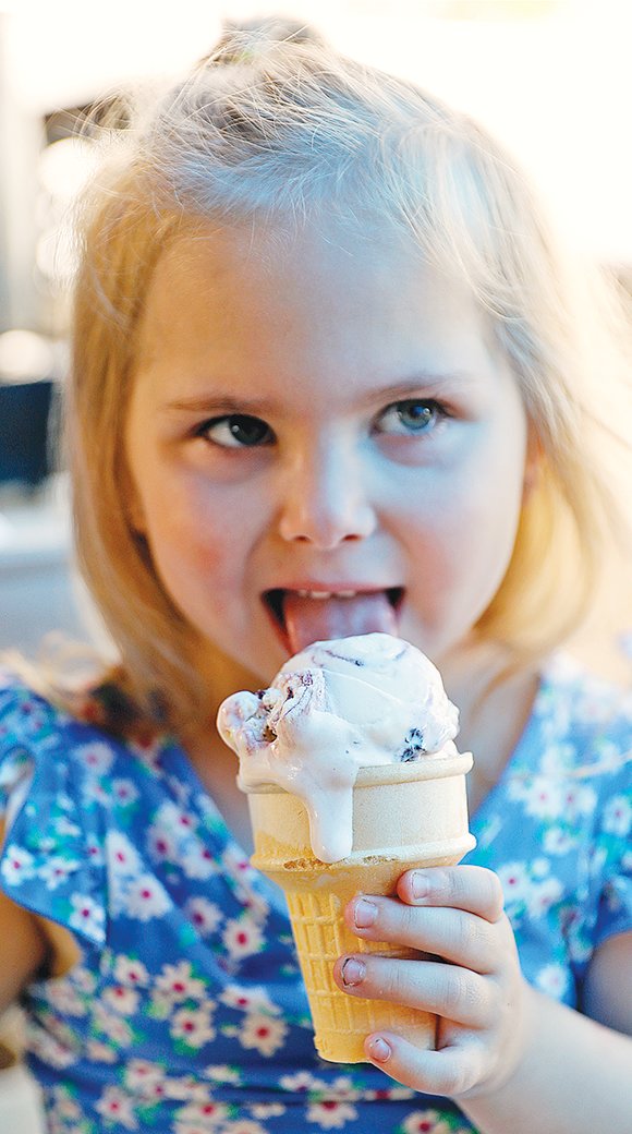 Five-year-old Allison Bajan, of Ely, licks a blueberry cheescake ice cream cone Sunday morning at the 41st Ely Blueberry/Art Festival.