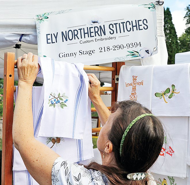 Ginny Stage, of Ely Northern Stitches, arranged her embroidery items just before the Ely Blueberry/Art Festival opened last Friday morning.