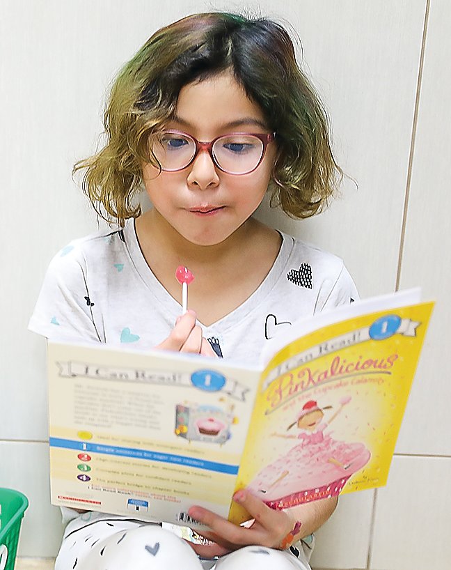 Third-grader Sherrie Peters focuses intently on her contribution toward the school’s goal of reading 100 books on Tuesday in honor of the 100th day of school.