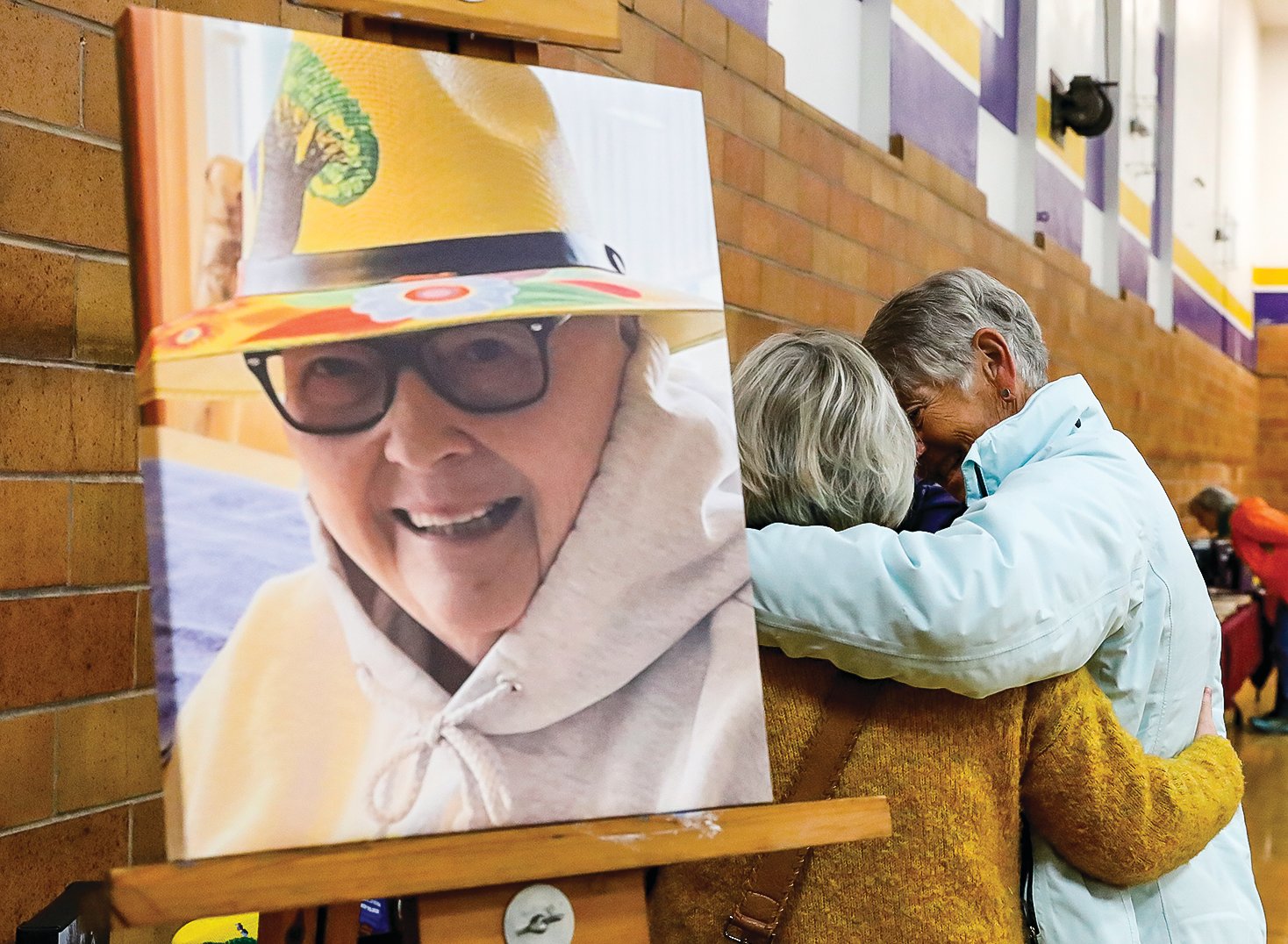 Old friends embrace next to a photo of the late Carol Alstrom, a much loved and respected former 
teacher at Tower-Soudan.