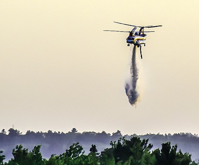 A Boeing Chinook CH-47D helicopter drops its 2,500 gallons of water on a wildfire that started just west of the Ely Golf Course on Saturday, May 27.