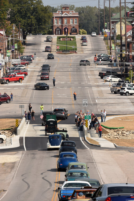 RIVER CITY CRUISERS car club members cross the Frene Creek Bridge on Highway 19/Market Street in Hermann on Friday morning following a dedication ceremony. The new bridge replaces a structure from 1930 and a 1930 Studebaker President owned by Tom and Kathy Durham and Hermann Crown Suites had the honor of leading the procession behind Hermann Police Chief Marlon Walker’s squad car.  The cruise across the new bridge included around 20 historic vehicles, a Hermann ambulance and fire truck.