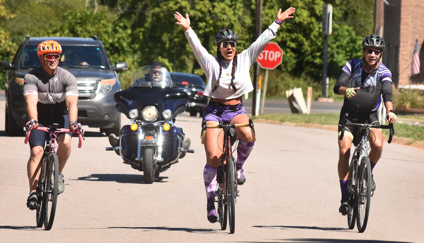 JEANNETTE KRUPP raises her arms Saturday morning on Fourth Street approaching Buschmann Park as she arrives from a 700-mile bicycle trip from Amarillo, Texas, to Owensville promoting her Stay Strong Krupp effort to end opioid overdose deaths and mental health awareness needs for those with addictions.