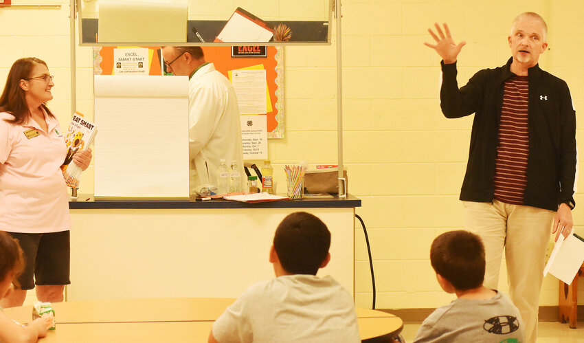 Richard POWERs, hired Monday as the R-2 School District’s administrative director for the ExcEL grant program, introduces University of Missouri Extension employee Nancy Stephan on Thursday after school during her presentation on food safety to Owensville Middle School students. OMS seventh-grade teacher Kevin Crowder, site administrator for the ExcEL program, is pictured in back. Powers returns after retiring from OMS where he taught eighth-grade math.