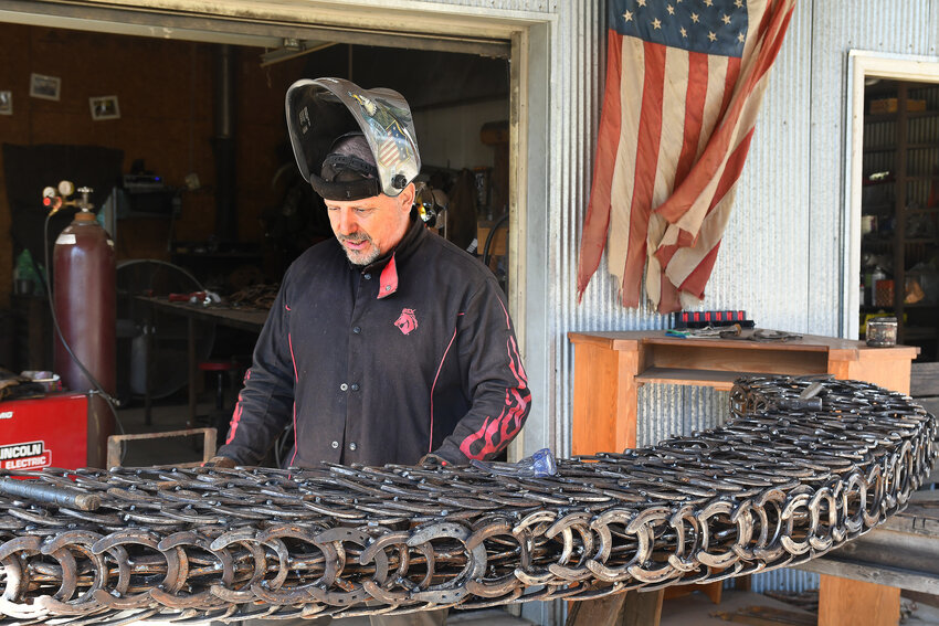 Tony Shanks takes a look at welds he made Oct. 1 as he creates a horseshoe-shaped sculpture made from horse shoes for a display planned in Owensville at City Hall adjacent to the Rock Island Trail State Park. The sculpture contains 2,400 horse shoes.