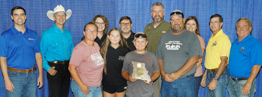 Gasconade County’s State Fair Farm Family for 2024 is Amanda and Josh Gruenke and their children, Lucy and Jase. The Gruenkes are pictured with State Fair, MU Extension, and Missouri Farm Bureau officials including (in back, from left) Blake Rollins, chief administrative officer, Missouri Farm Bureau, Ed Adams, Missouri State Fair commissioner, Sarah Traub, interim associate vice chancellor for MU Extension and director of Education and Impact, Rob Kallenbach, MU associate dean of Extension and senior program director of Agriculture and Environment, Jason Moore, State Fair director, Jamie Johansen, State Fair commissioner, Todd Hayes, vice president of Missouri Farm Bureau, and Randy Little, fair commissioner.