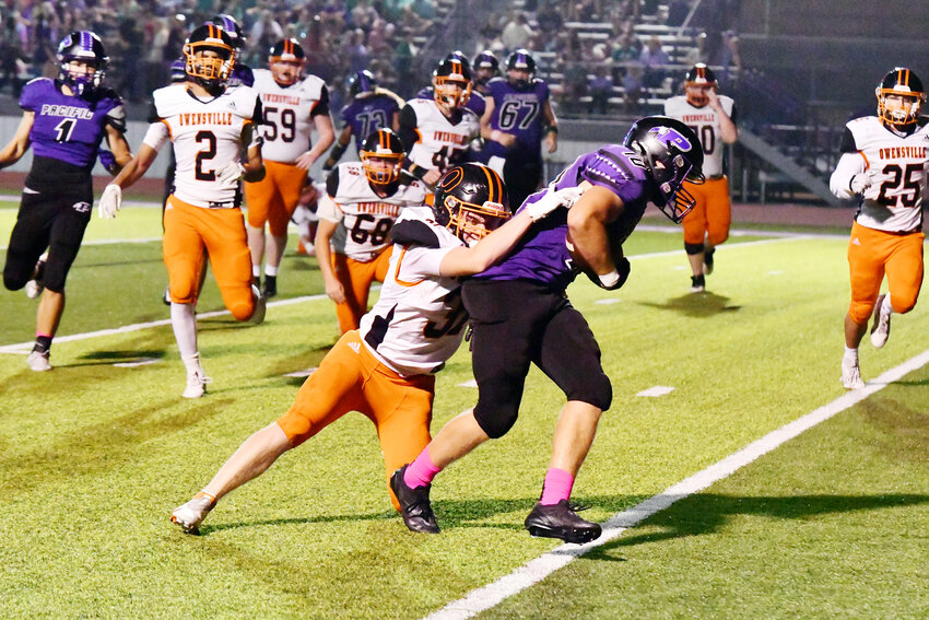 Connor Wellman (above, center) grabs a hold of Pacific’s Trey Kulick looking to bring him down during Owensville’s 62-14 road loss Friday night against the host Indians.