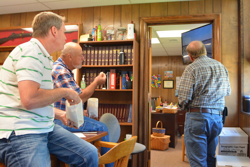 Western District Commissioner Patrick Kleffner (left), Eastern District Commissioner Doug Drewel and Presiding Commissioner Victor Stratman eat popcorn while watching videos about solar farms during the May 22 meeting.