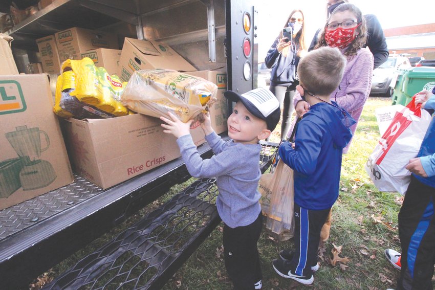 PACKING IT IN: Four-year old Camden Cote joined with his parents and other Warwick Police and their families Saturday morning to load food donations made in the recent department drive into a UPS truck for delivery to the Westbay Community Action Marketplace on Jefferson Boulevard.