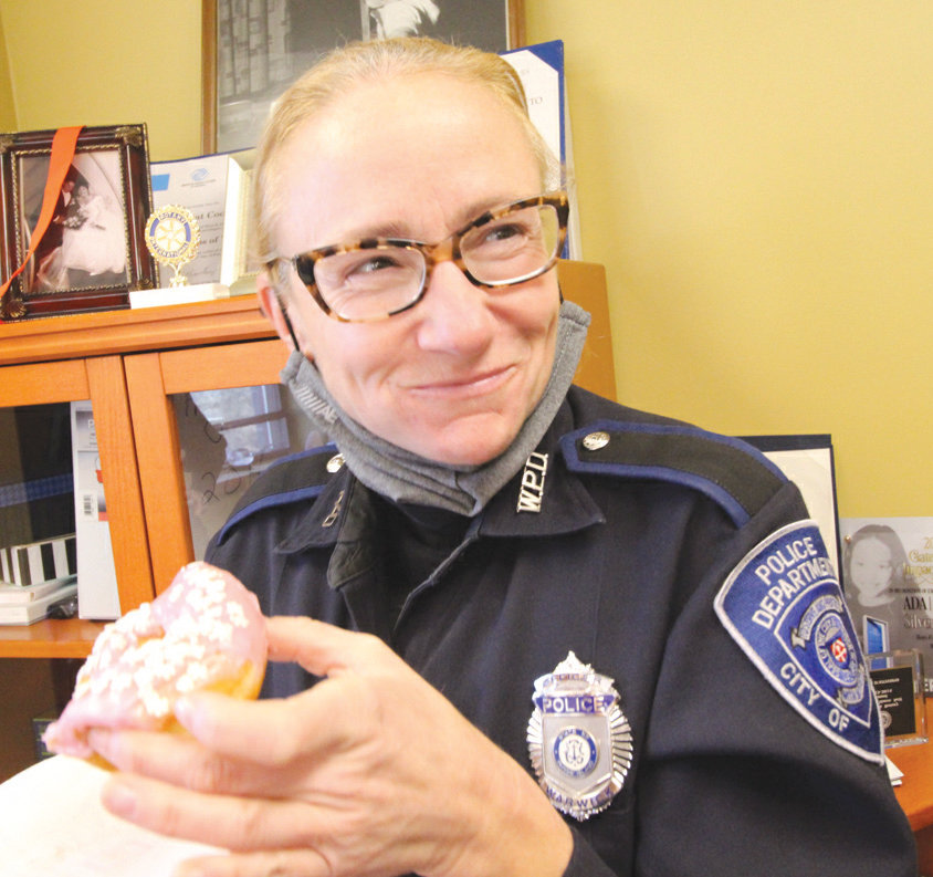 ON DUTY FOR OTHERS:&nbsp; Officer Jill Marshall of the Warwick Police Department has put in a long career of helping her community. Here she enjoys a donut, a token of appreciation from the Warwick Boys and Girls Clubs when she and other officers delivered toys for the club&rsquo;s Christmas shop.