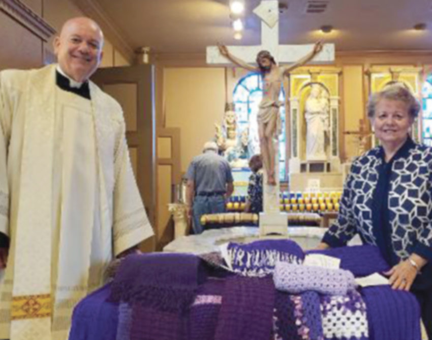 BLESSINGS TO YOU: Father Ledoux and Kathy McKeon Bastia, representing the Regina Coeli Society, pose with the 13 shawls to be donated to victims of elder abuse.