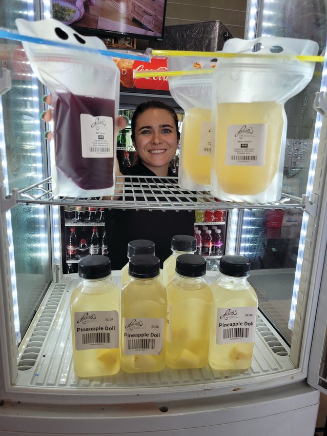 LUIGI&rsquo;S LIQUORS: Luigi&rsquo;s Restaurant &amp; Gourmet Express Dining Room Manager Mia Bucco adjusts a few cocktails-to-go in a refrigerated case near the cash register. Luigi&rsquo;s offers many options, including Pineapple Doli, red and white Sangria.