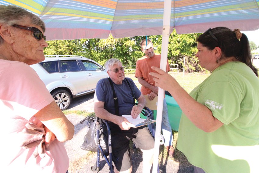 POND NEIGHBORS: Ken and Marge Allstrom and their son Peter talk with Christine Kellerman, organizer of the Friends of Gorton Pond at Saturday&rsquo;s meeting and pond cleanup.