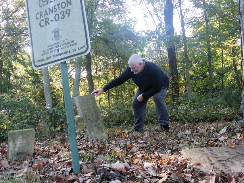 AT THE FULLER LOT:&nbsp;Cranston Historical Cemeteries Commission Chairman David Guiot examines gravestones in the Fuller Lot. The flat headstone he has his hand on is for Ebenezer Fuller, the mill owner for whom the cemetery is named.