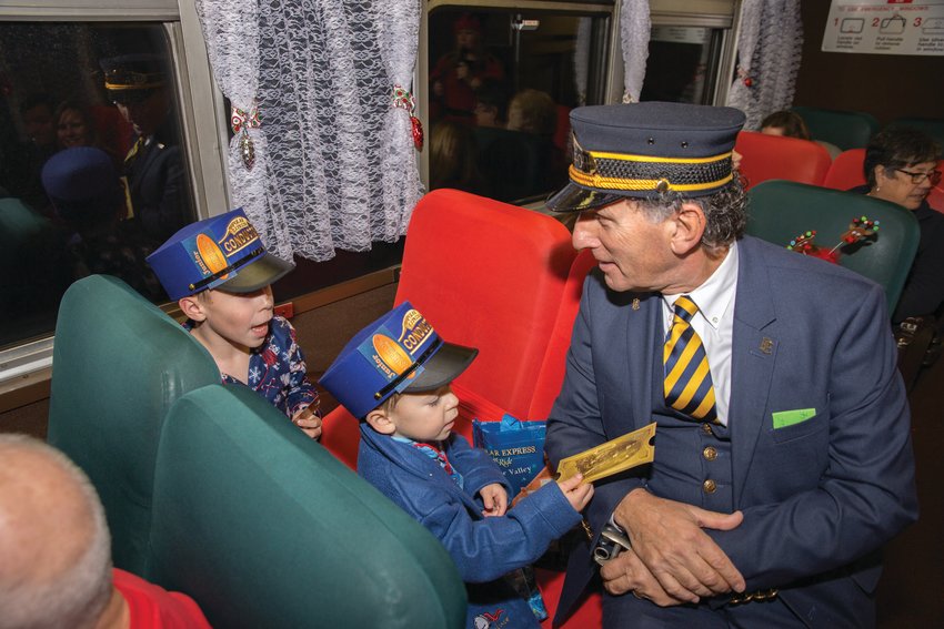 ALL ABOARD!&nbsp;Conductor Bob and junior conductors share a moment aboard the Blackstone Valley Polar Express Train Ride.