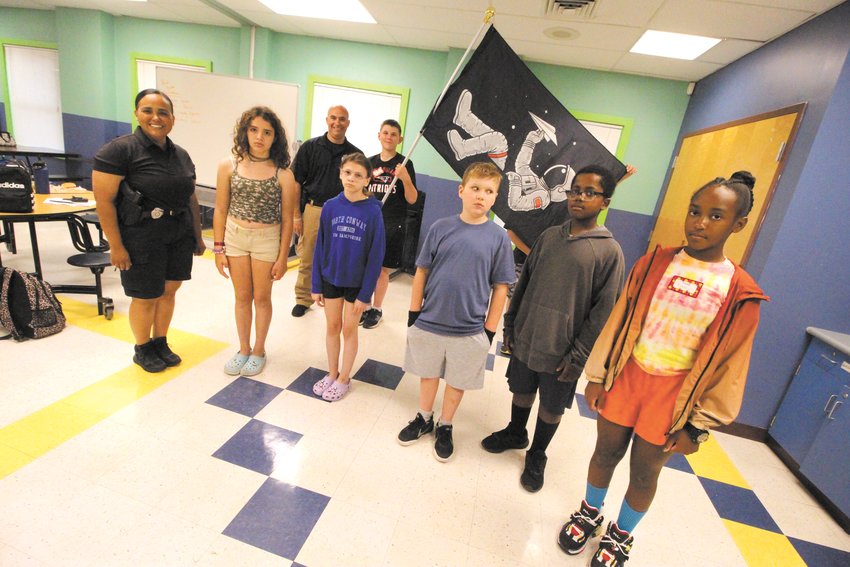 THEIR FLAG: Campers in the Warwick Police Department Leadership Camp that started Monday at the Oakland Beach branch of the Warwick Boys and Girls Clubs chose an outer space banner under which to gather as they will be &ldquo;exploring&rdquo; new opportunities. School resource officers Rose Michel and Al Marano are running this session of the camp. (Warwick Beacon photo)