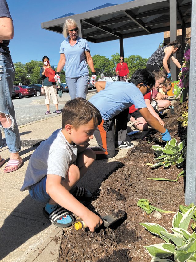 MAKING ROOM FOR FLOWERS: Rory Celeste, 5, uses a hand trowel and digs into the soil in front of Central Library; he is clearing space to make room for peonies.