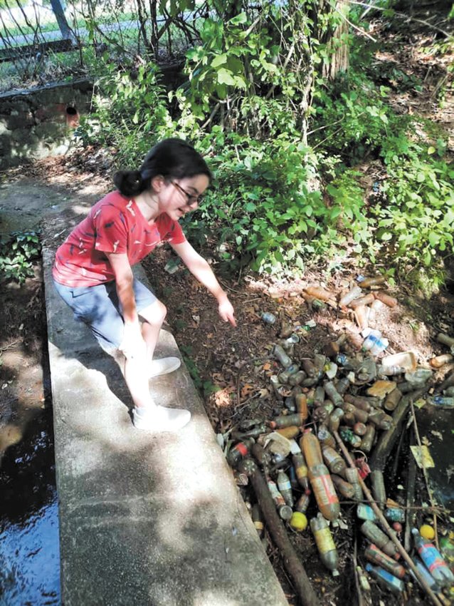 TOO MUCH TRASH: Charlie Wren points at the collection of water bottles that campers discovered with their counselors while walking on a trail to check out the local water source. (Submitted photo)