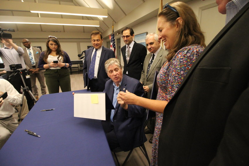 SHE GOT TO KEEP THE PEN: Gov. Dan McKee hands Senator Meghan E. Kallman the pen he used to sign housing legislation she sponsored. Looking on from left are House Speaker K. Joseph Shekarchi, RI Secretary of Housing Josh Saal and US Senator Jack Reed. (Herald photo)