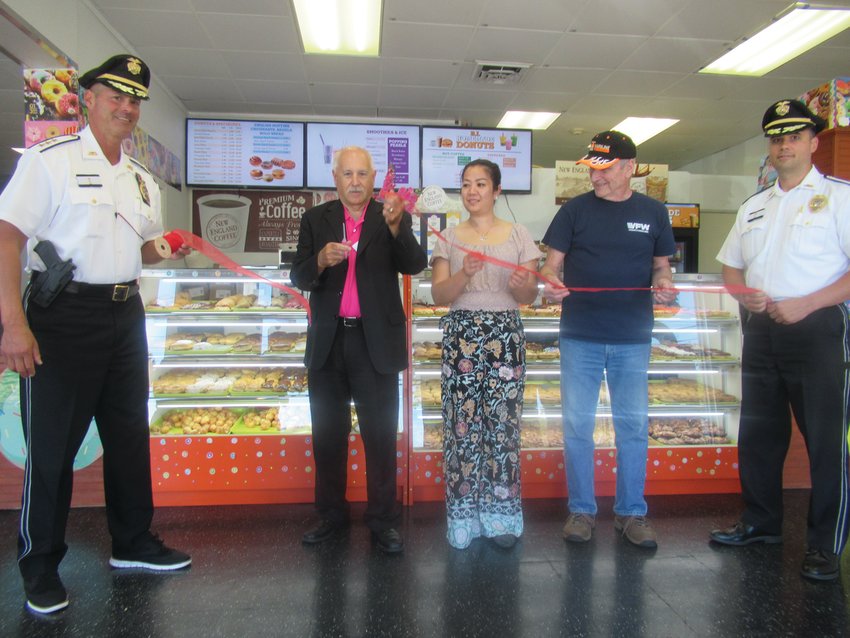 OFFICIAL OPENING: With JPD Chief Joseph P. Razza (left) and Deputy Chief Mark Vieira (right) holding a red ribbon alongside Sophal Cheng and Bob Moulton, Mayor Joseph Polisena performs the ceremonial cutting at last Thursday&rsquo;s Grand Opening of Rhode Island Homemade Donuts in Johnston.