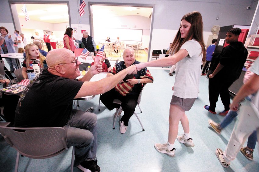 A PARADE STOPPER: Army Veteran Rick Bean gets a fist bump from Skylar Hawes as Veterans Memorial Middle School students paraded around the school cafeteria Monday during a  breakfast hosted by the school. The veterans attending were family members and friends of school students and staff.(Warwick Beacon photo)