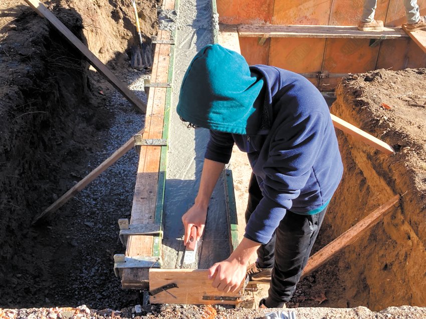 FLATTENING THE SURFACE: David Sosa uses a trowel to finish the top of the wall. (Herald photos)