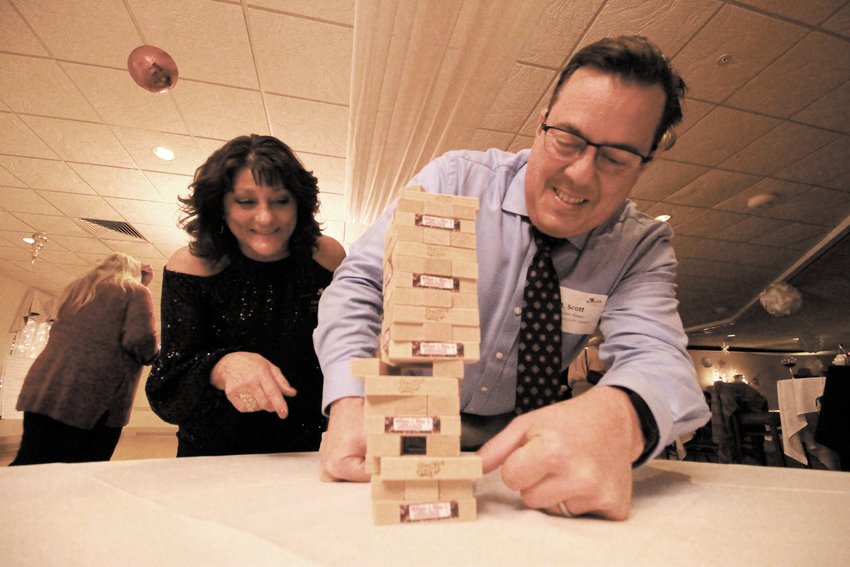 HARDLY ANY WIGGLE ROOM: Scott Hayes looks to pull a block from the tower without having it tumble  and then celebrates his success as his partner Cheryl Cady looks on. Both are from Navigant Credit Union, one of several chamber members to sponsor the holiday business after hours event last Thursday at the Valley Country Club.