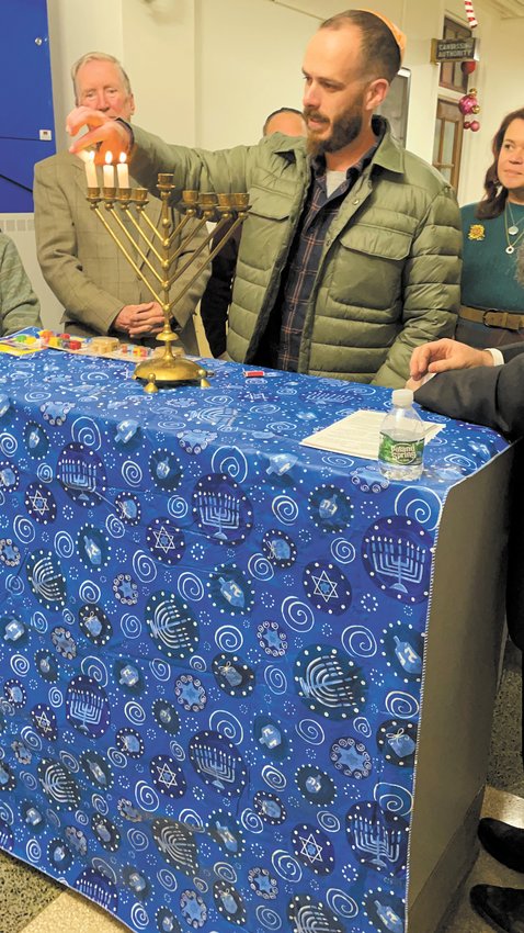 GETTING LIT AT CITY HALL: Jake Dwares of Cranston, has the honor of lighting the third and final candle.