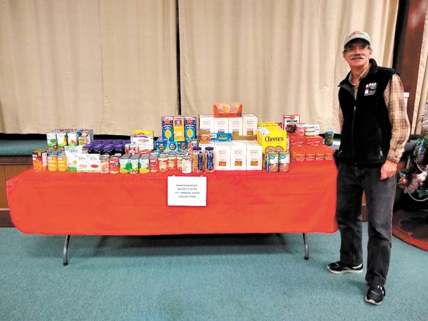 PARTY DONATIONS: Mike Distefano a long time member of the Photographic Society of Rhode Island with some of the food donated at the society&rsquo;s annual Christmas party.  (Submitted photo)