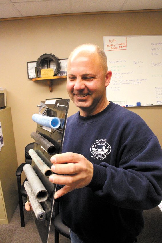 TYPES OF WATER PIPES: Michael DiPetrillo holds a display of pipes commonly used for home water service. The bottom pipe with the smallest opening is a lead pipe. (Warwick Beacon photo)