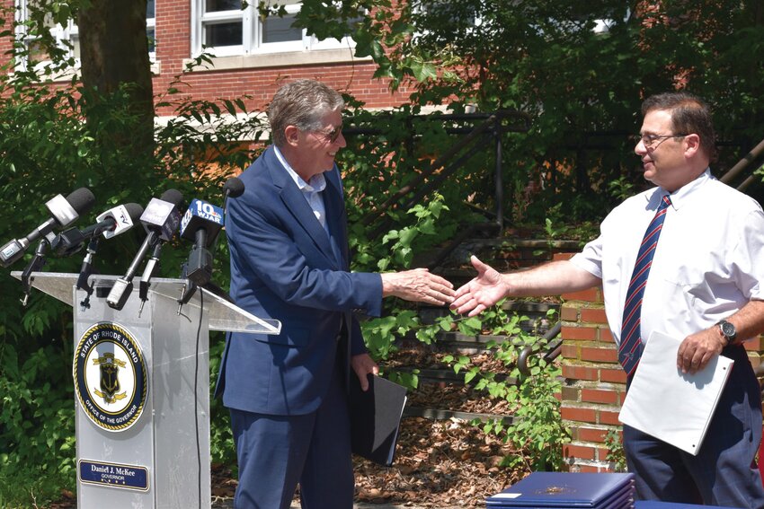 A SHAKE ON HOUSING: With the former Aldrich Junior High as the backdrop Governor Daniel McKee  and House Speaker K. Joseph Shekarchi greet one another yesterday at a ceremonial signing of 5 of 13 housing bills Shekarchi backed in the session of the General Assembly.