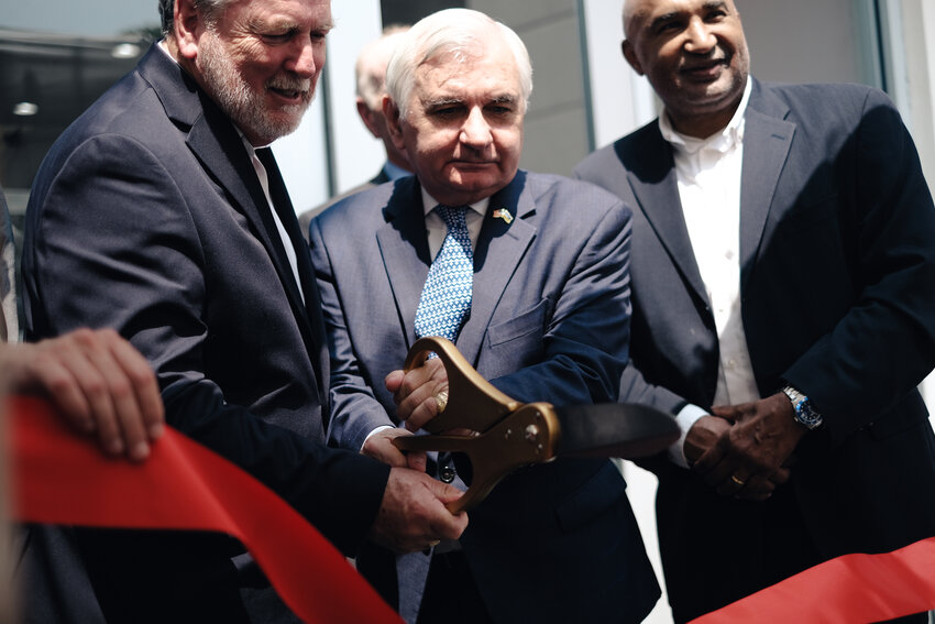 CUTTING RED TAPE:  Senator Reed, with an assist from RISLA Executive Director Charles Kelley, successfully snips through the ribbon and declares the College Planning Center open. (Herald Photo by Will Steinfeld)