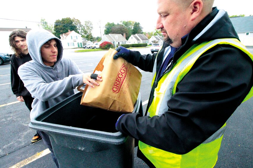 READY TO SHRED: Cranston East student Ethan Peloquin hands over a bag of documents destined to the shredder to Chris Laflamme of the shredding company.